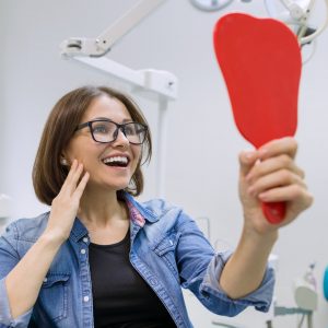 woman-patient-looking-in-the-mirror-at-the-teeth-sitting-in-the-dental-chair.jpg